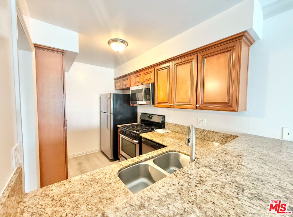 821 3rd Street, Unit 305 Santa Monica, CA 90403 - Photo 13 of 13 a kitchen with granite countertop sink refrigerator and cabinets