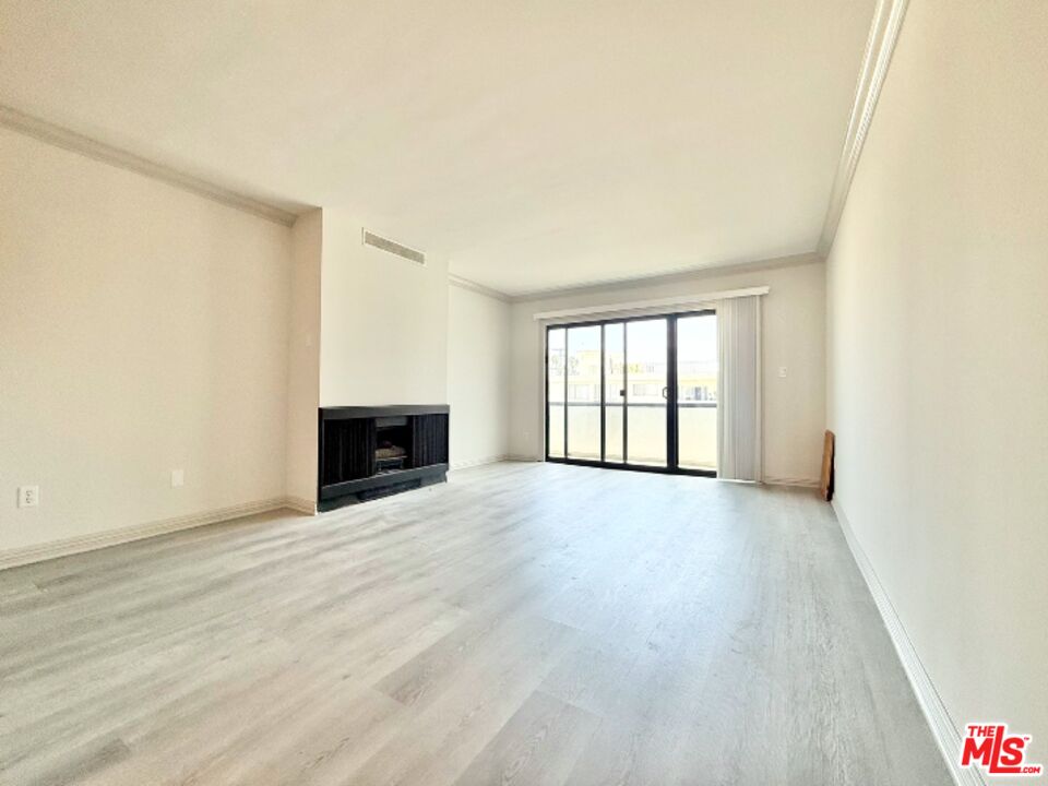 821 3rd Street, Unit 305 Santa Monica, CA 90403 - Photo 9 of 13 an empty room with wooden floor and fireplace