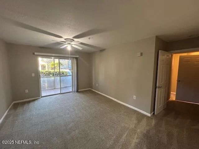 an empty room with windows and chandelier fan