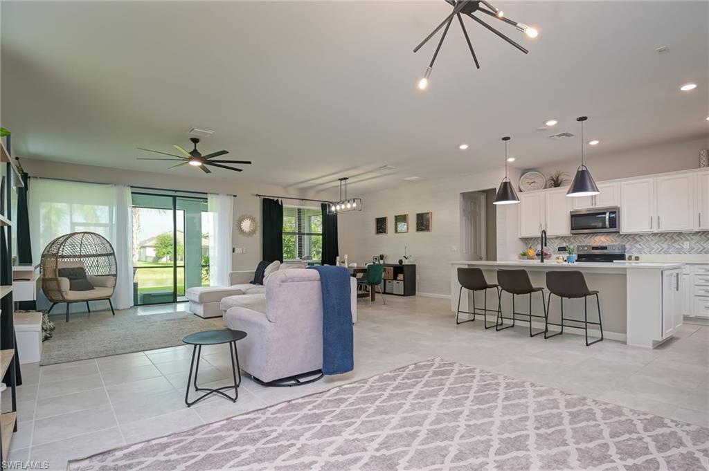 2137 Clementine Street Naples, FL 34120 - Photo 7 of 32 a living room with furniture a dining table and a fireplace
