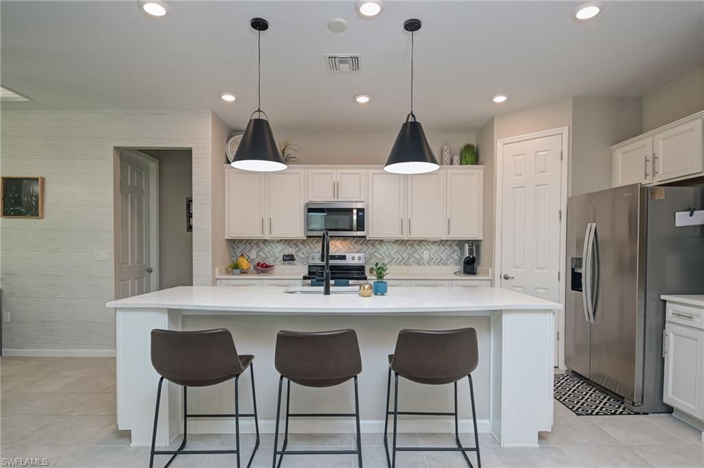 2137 Clementine Street Naples, FL 34120 - Photo 8 of 32 a kitchen with stainless steel appliances a dining table chairs sink and wooden floor