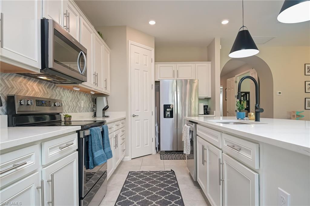 2137 Clementine Street Naples, FL 34120 - Photo 10 of 32 a kitchen with stainless steel appliances granite countertop a sink and a stove