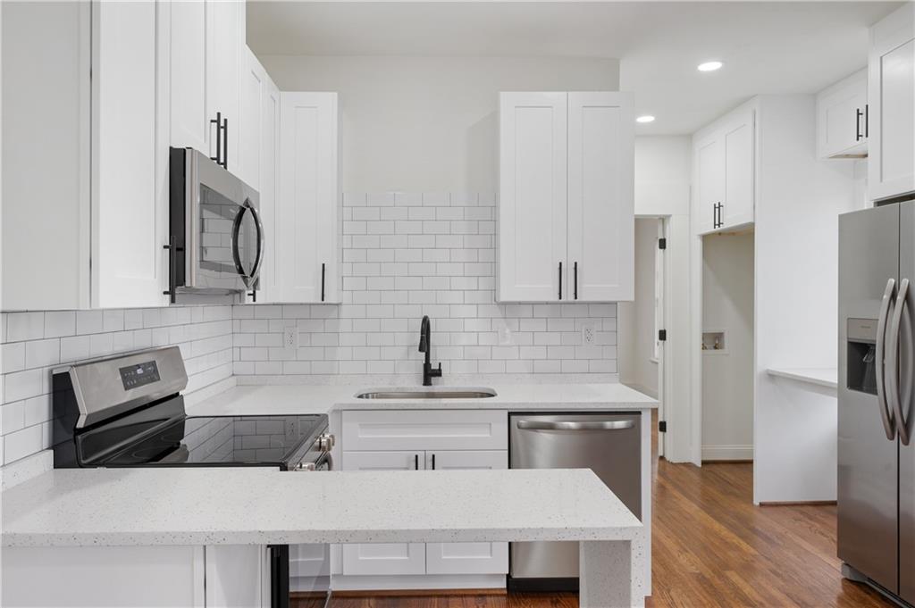 405 4th Street Northeast, Unit 24 Atlanta, GA 30308 - Photo 7 of 19 a kitchen with stainless steel appliances a refrigerator a sink a stove and white cabinets