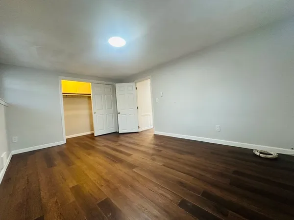 a view of empty room with wooden floor and closet