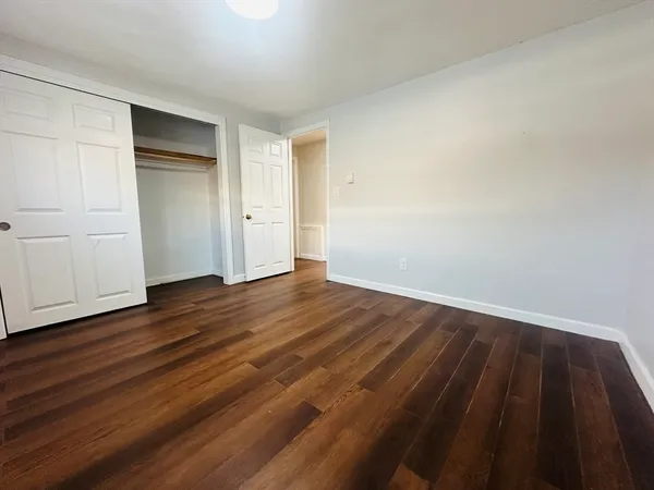 a view of an empty room with wooden floor and closet