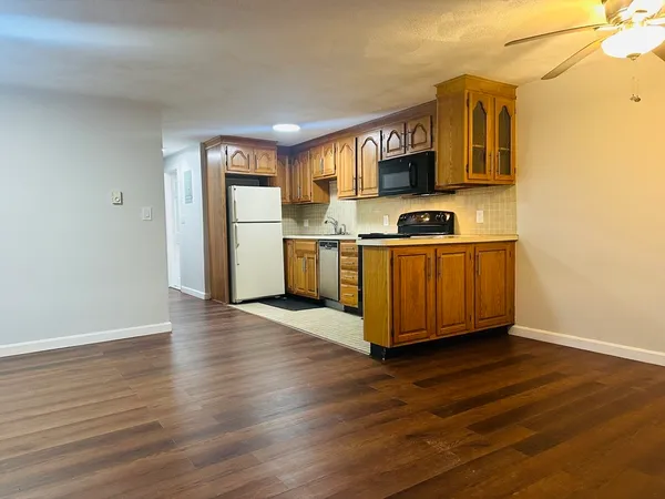 a kitchen with stainless steel appliances granite countertop a stove top oven a sink dishwasher and a refrigerator with wooden floor