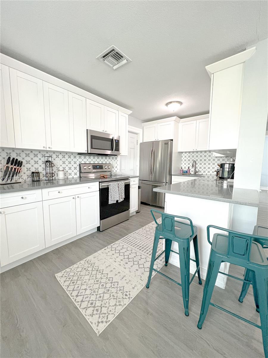 515 Valley Forge Road West Palm Beach, FL 33405 - Photo 6 of 9 a kitchen with stainless steel appliances kitchen island granite countertop a table chairs sink and cabinets