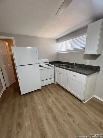 a kitchen with granite countertop white cabinets and white appliances