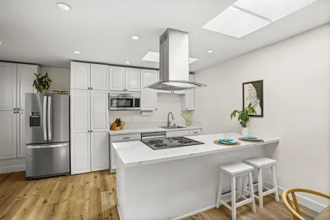 a kitchen with stainless steel appliances granite countertop a sink a stove a refrigerator cabinets a dining table and chairs