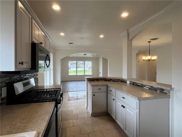 a kitchen with stainless steel appliances granite countertop a stove a sink and a microwave