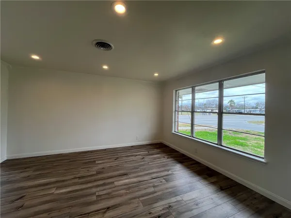 an empty room with wooden floor and windows
