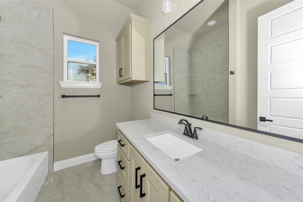 1057 Vh Ranch Poolville, TX 76487 - Photo 24 of 38 a bathroom with a granite countertop sink a large mirror a toilet and a bathtub