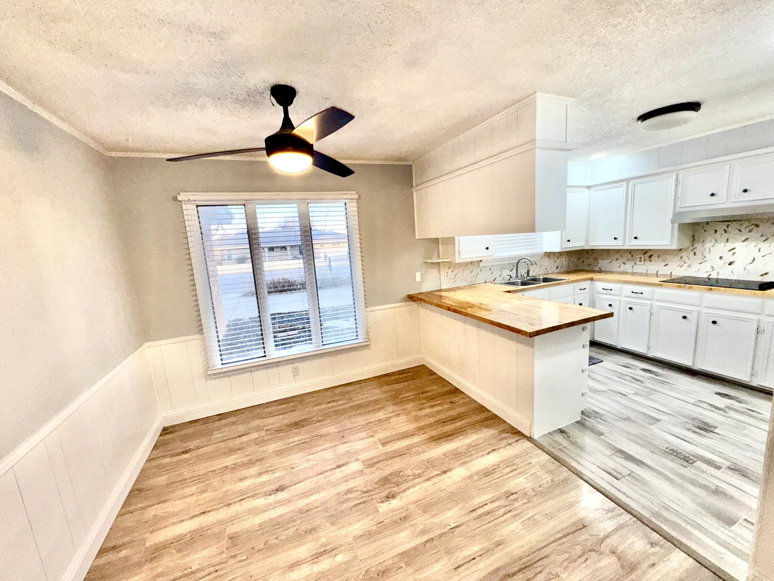 5415 73rd Street Lubbock, TX 79424 - Photo 10 of 13 a kitchen with a stove a sink dishwasher and a dining table with wooden floor