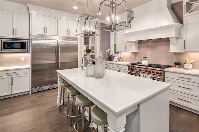 a kitchen with stainless steel appliances a table chairs and a refrigerator
