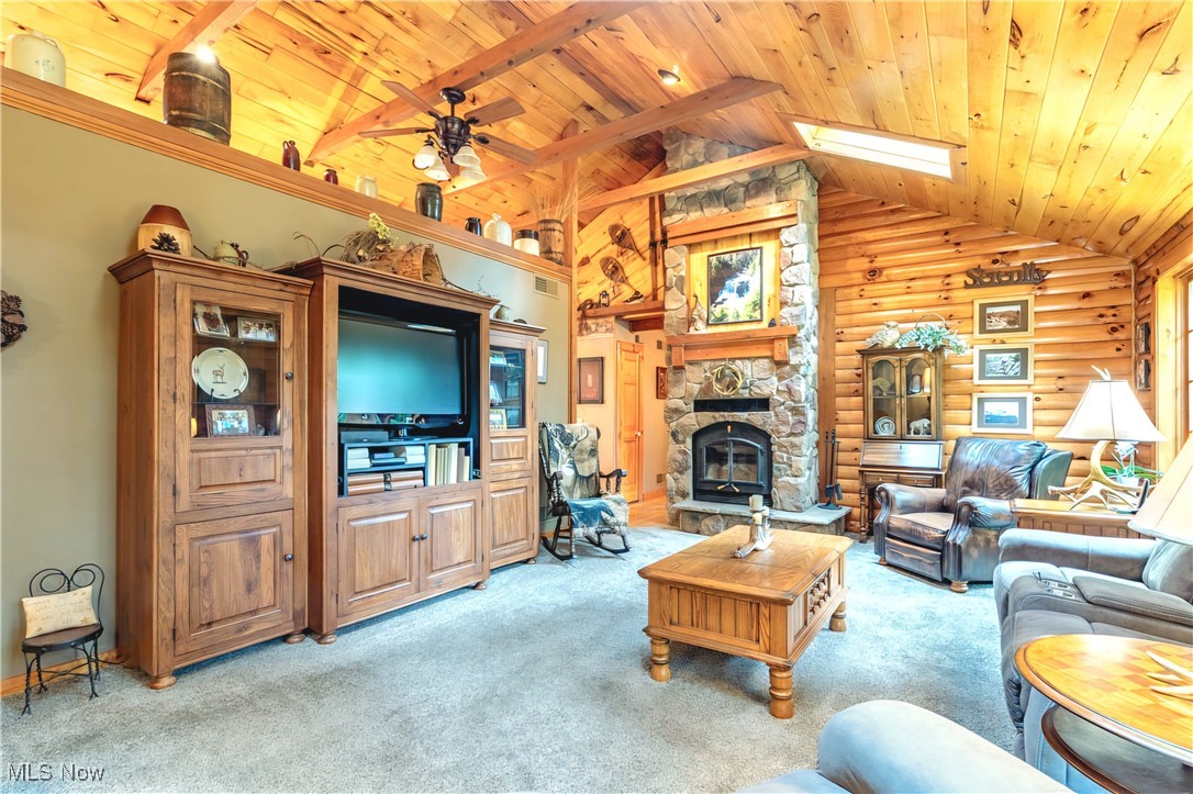 49144 Hickman Road Calcutta, OH 43920 - Photo 8 of 23 Living room with rustic walls, wood ceiling, ceiling fan, a fireplace, and light carpet