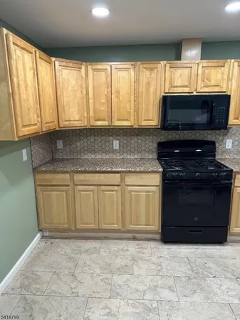 a kitchen with granite countertop a stove top oven microwave and cabinets