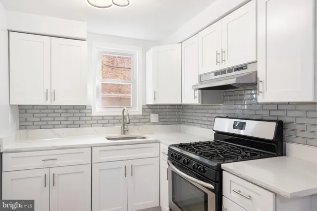a kitchen with granite countertop a sink a stove and cabinets