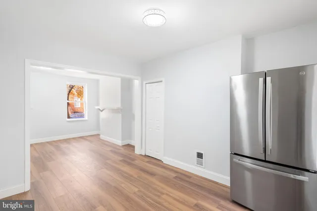 a view of an empty room with window and wooden floor