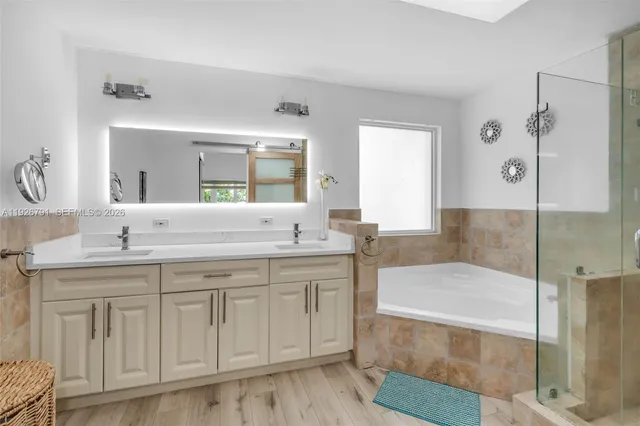 a spacious bathroom with a granite countertop sink a mirror and a bathtub