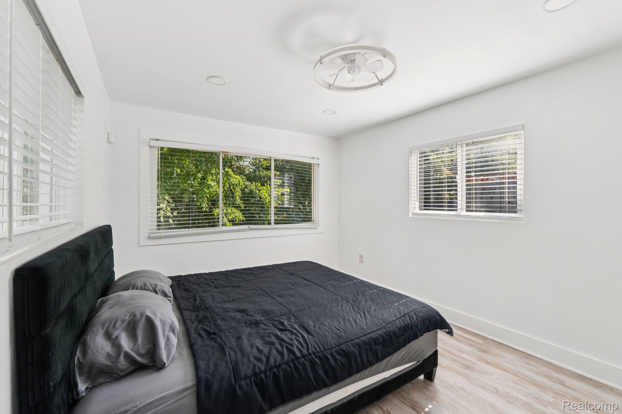 16210 Inverness Street Detroit, MI 48221 - Photo 13 of 29 Bright room featuring multiple windows with blinds, wood-finish flooring, recessed lighting, and a modern ceiling fan
