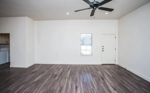 a view of a room with wooden floor and a ceiling fan