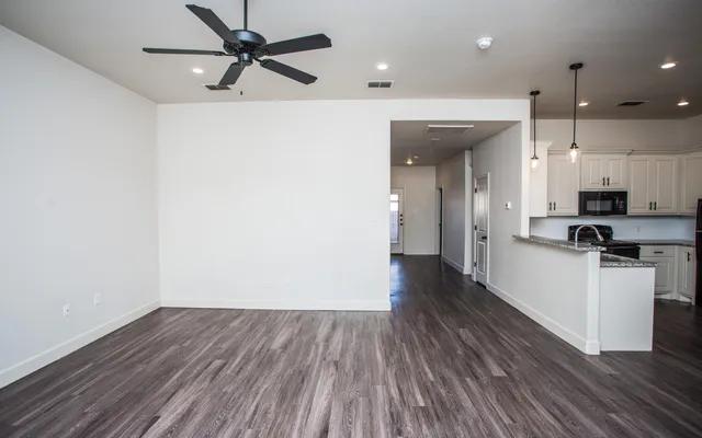 a view of a kitchen with a sink a ceiling fan and wooden floor