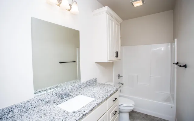 a bathroom with a granite countertop sink a toilet and shower