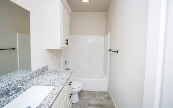 a bathroom with a granite countertop sink a toilet and shower