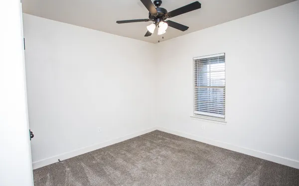 an empty room with a window and a fan