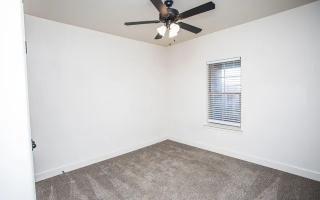 an empty room with a window and a fan