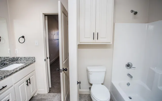 a bathroom with a granite countertop toilet and a sink