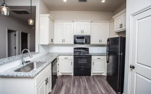 a kitchen with granite countertop a refrigerator stove and sink