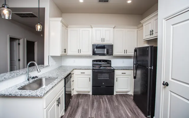 a kitchen with granite countertop a refrigerator stove and sink