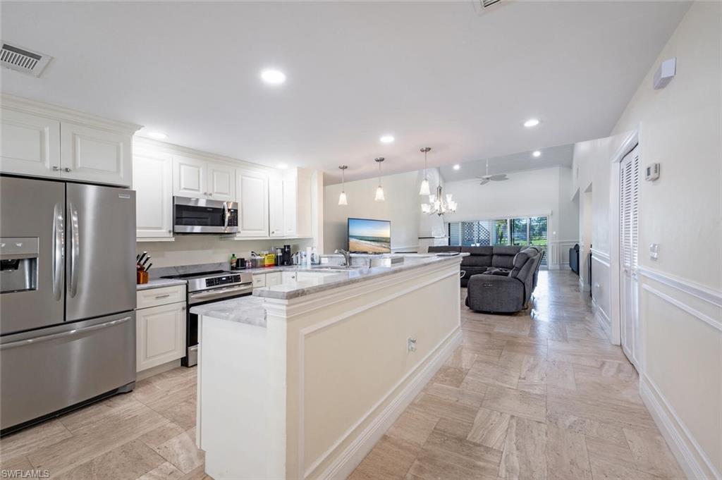 a large white kitchen with a refrigerator a stove top oven a sink and cabinets