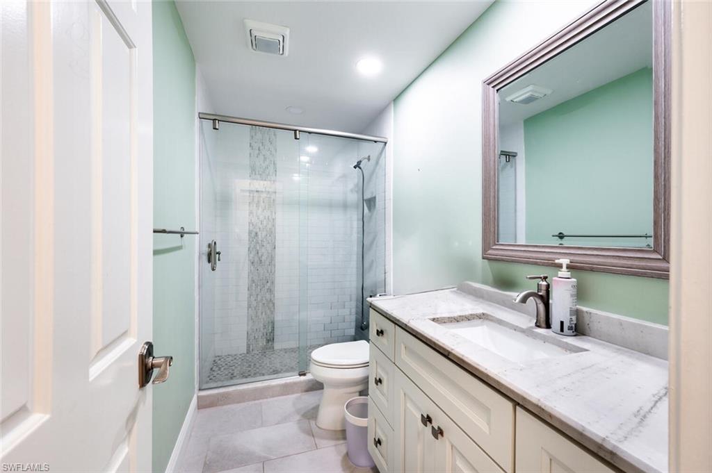 640 Augusta Boulevard Naples, FL 34113 - Photo 14 of 29 a bathroom with a granite countertop sink a toilet and a large mirror
