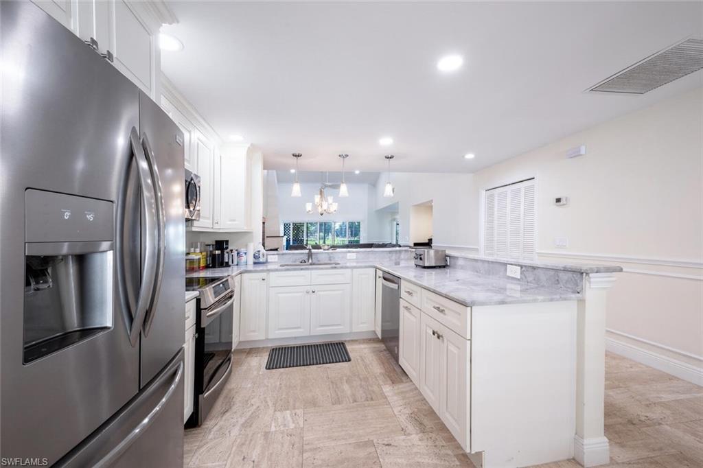 640 Augusta Boulevard Naples, FL 34113 - Photo 2 of 29 a kitchen with white cabinets and stainless steel appliances