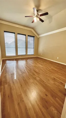 an empty room with wooden floor and ceiling fan