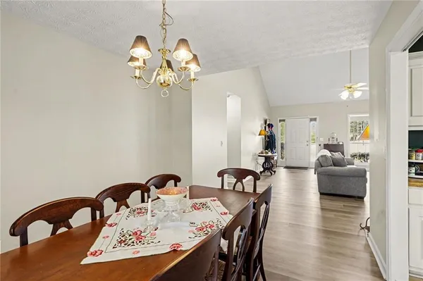 a view of a dining room and livingroom with furniture wooden floor a chandelier