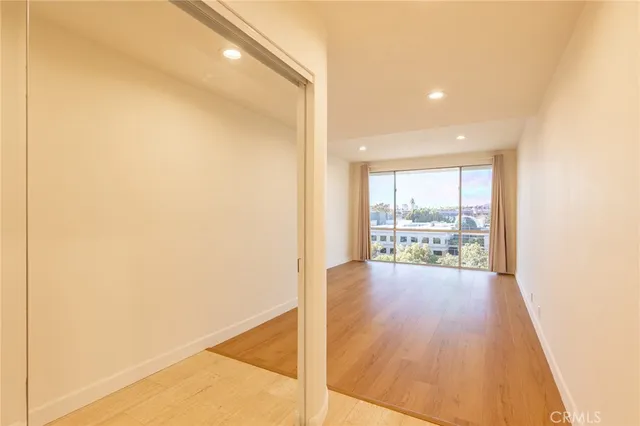 a view of a big room with wooden floor and windows