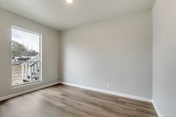 a view of an empty room with a window and wooden floor