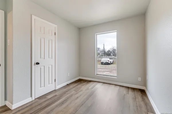 an empty room with wooden floor and windows