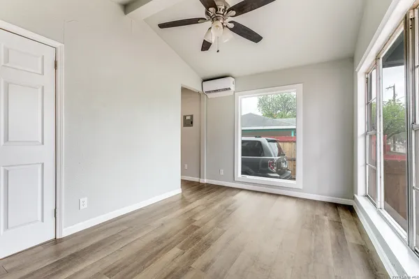 a view of an empty room with wooden floor and a window