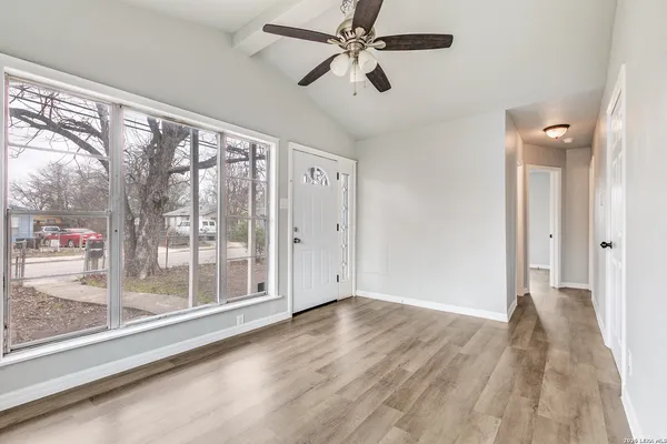 a view of empty room with wooden floor and fan