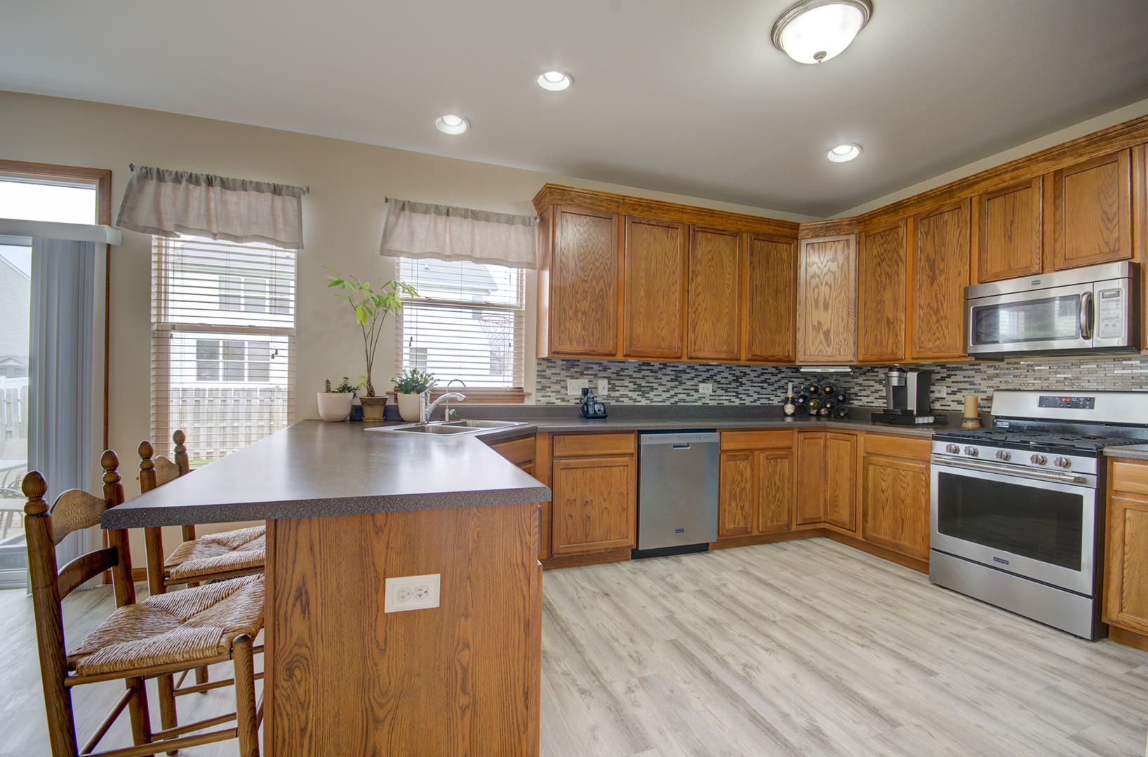 6417 Roth Drive Joliet, IL 60431 - Photo 8 of 32 a kitchen with stainless steel appliances granite countertop wooden cabinets a stove top oven a sink and dishwasher with wooden floor