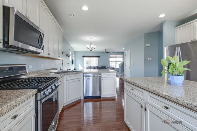 a kitchen with kitchen island granite countertop a sink cabinets and stainless steel appliances