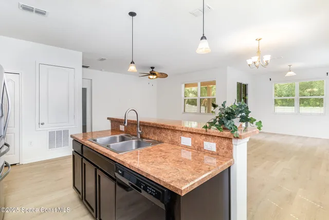a room with kitchen island a sink and a chandelier