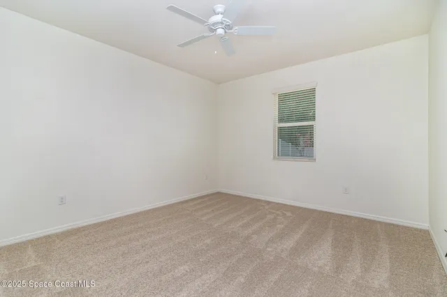 an empty room with a window and ceiling fan