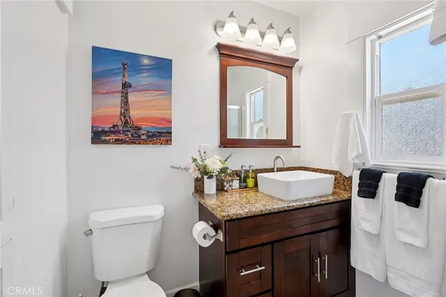 a bathroom with a granite countertop sink and a toilet