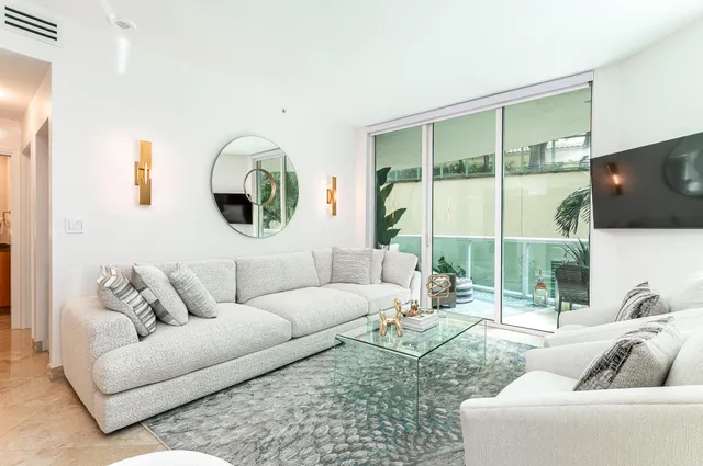 a living room with furniture a flat screen tv and a large window