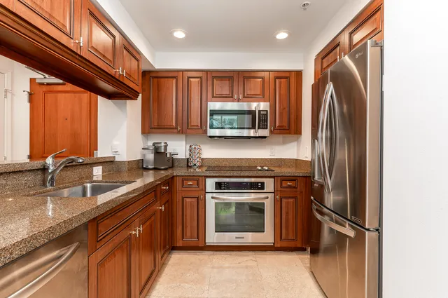 a kitchen with stainless steel appliances granite countertop a refrigerator a stove a sink and a microwave